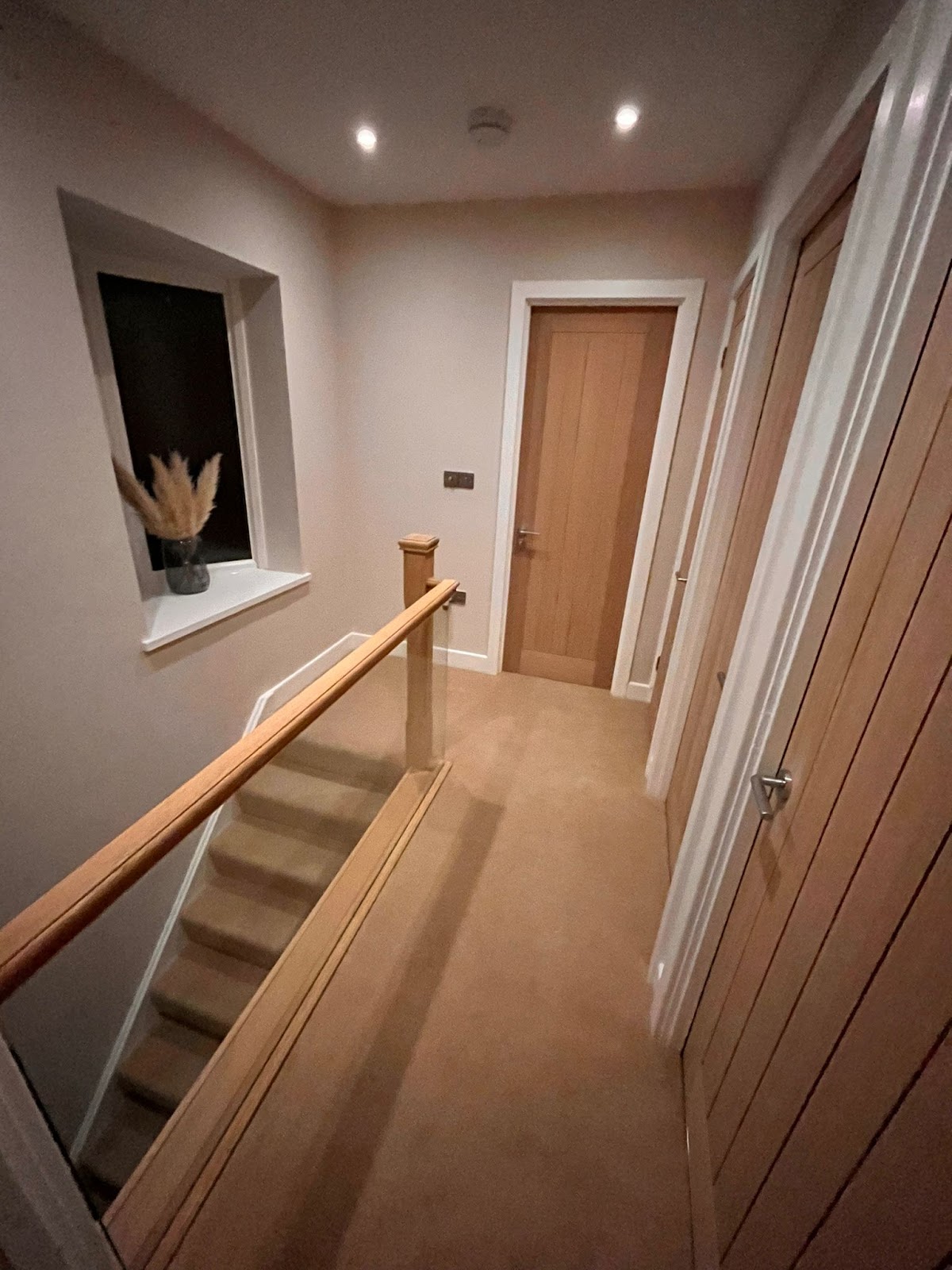 Landing with oak doors and an oak and glass bannister